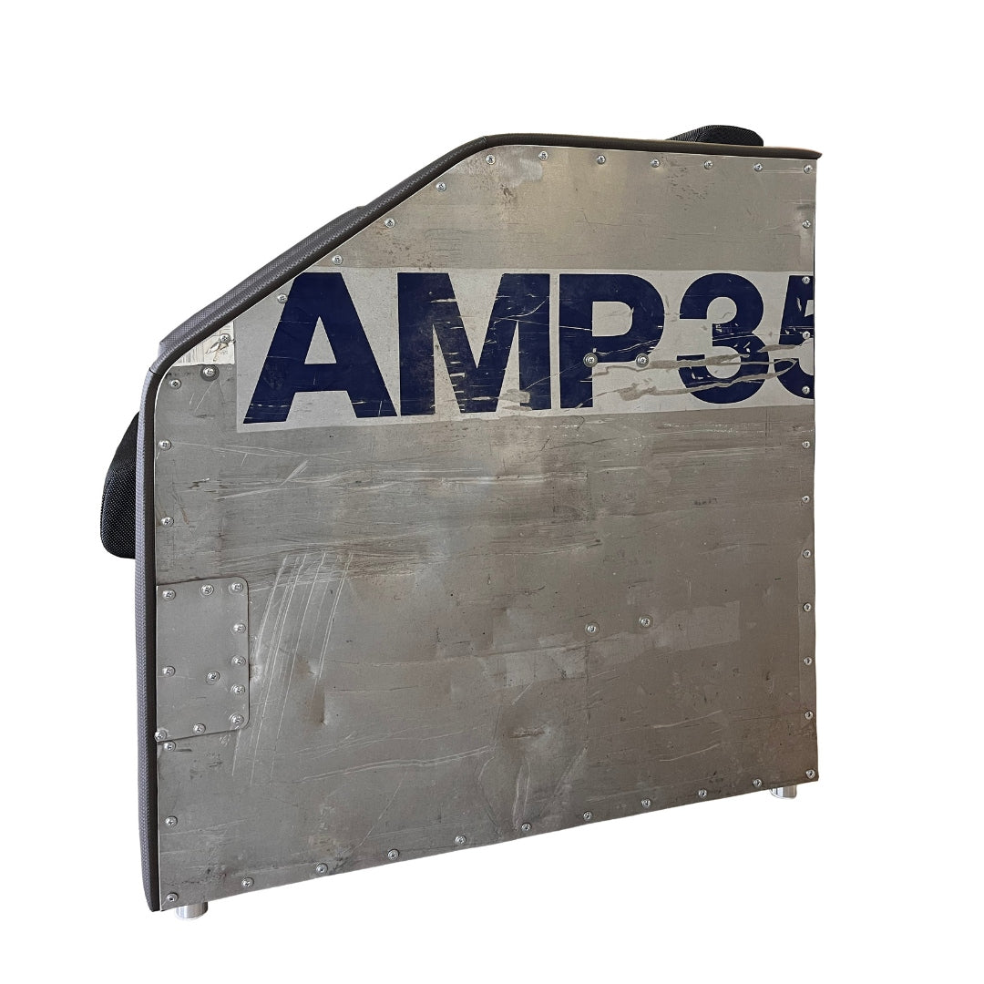 Rechteckiges Metallpanel mit AMP35 in Blau, sichtbaren Nieten und Gebrauchsspuren, gepolstert mit grauem Rand.