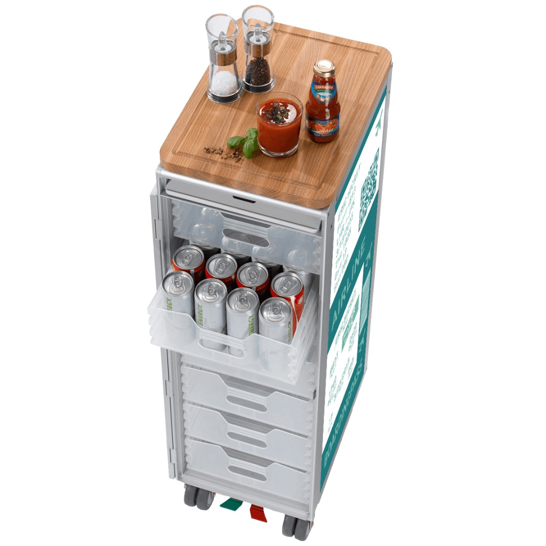 Moderner Airline-Servierwagen aus Metall mit transparenten Schubladen, Holzablage und Getränk mit Basilikum.