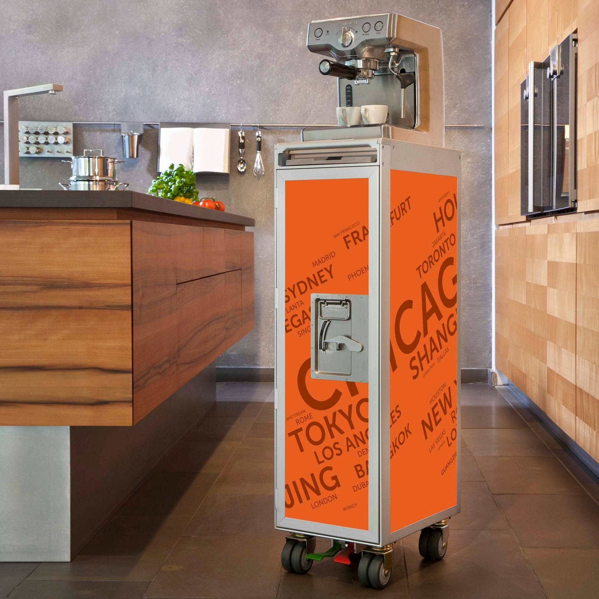 Moderner Kücheninnenraum mit orangefarbenem Skypak Airline Trolley und silberner Espressomaschine