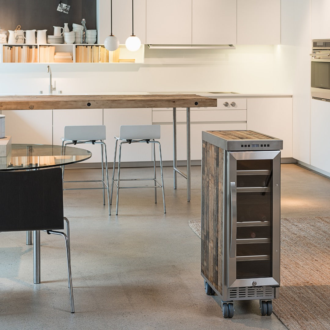 Moderner Küchenraum mit weißem Mobiliar, rustikalem Getränkekühlschrank auf Rollen und Holzinsel mit grauen Barhockern.