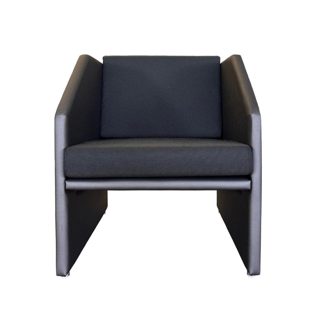 Moderner, minimalistischer Sessel mit dunkelgrauen, strukturierten Kissen und eckigen Seitenarmen