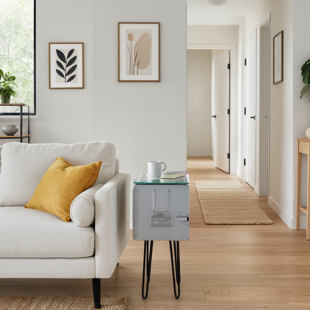 Modernes Wohnzimmer mit beigem Sofa und senffarbenem Kissen, Metalltisch, minimalistischer Kunst an der Wand und hellem Flur.