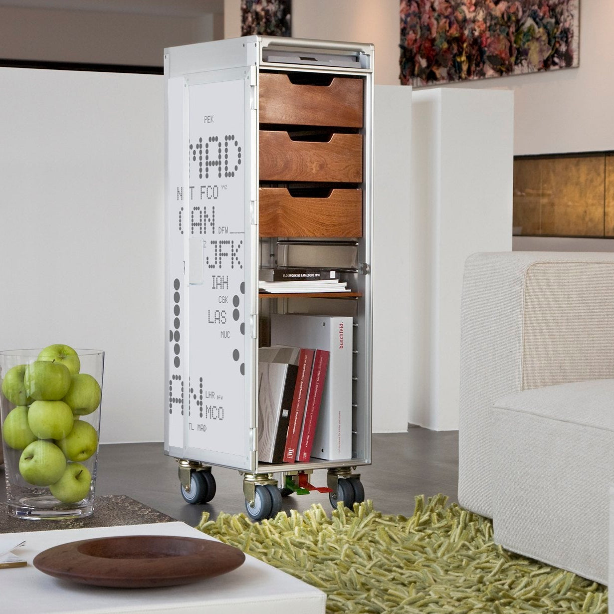 Schmaler Stauraumschrank mit Flugplatzcodes, Holzschubladen und offenen Fächern in modernem Wohnambiente.