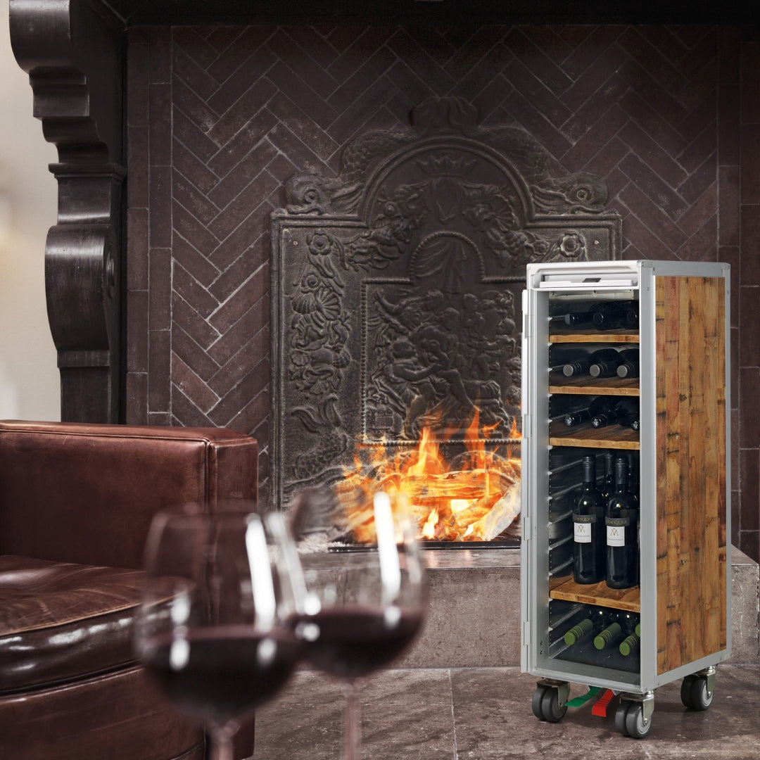 Weinkühlschrank aus Metall und Holz neben Kamin mit braunem Ledersessel und Rotweingläsern