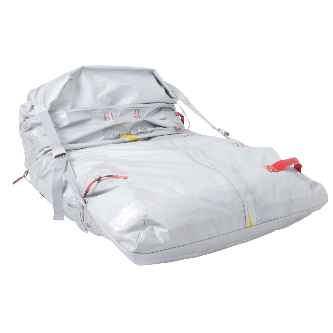 Große graue Industrieplane mit weißen Gurten, Metallschnallen und roten sowie gelben Griffen.