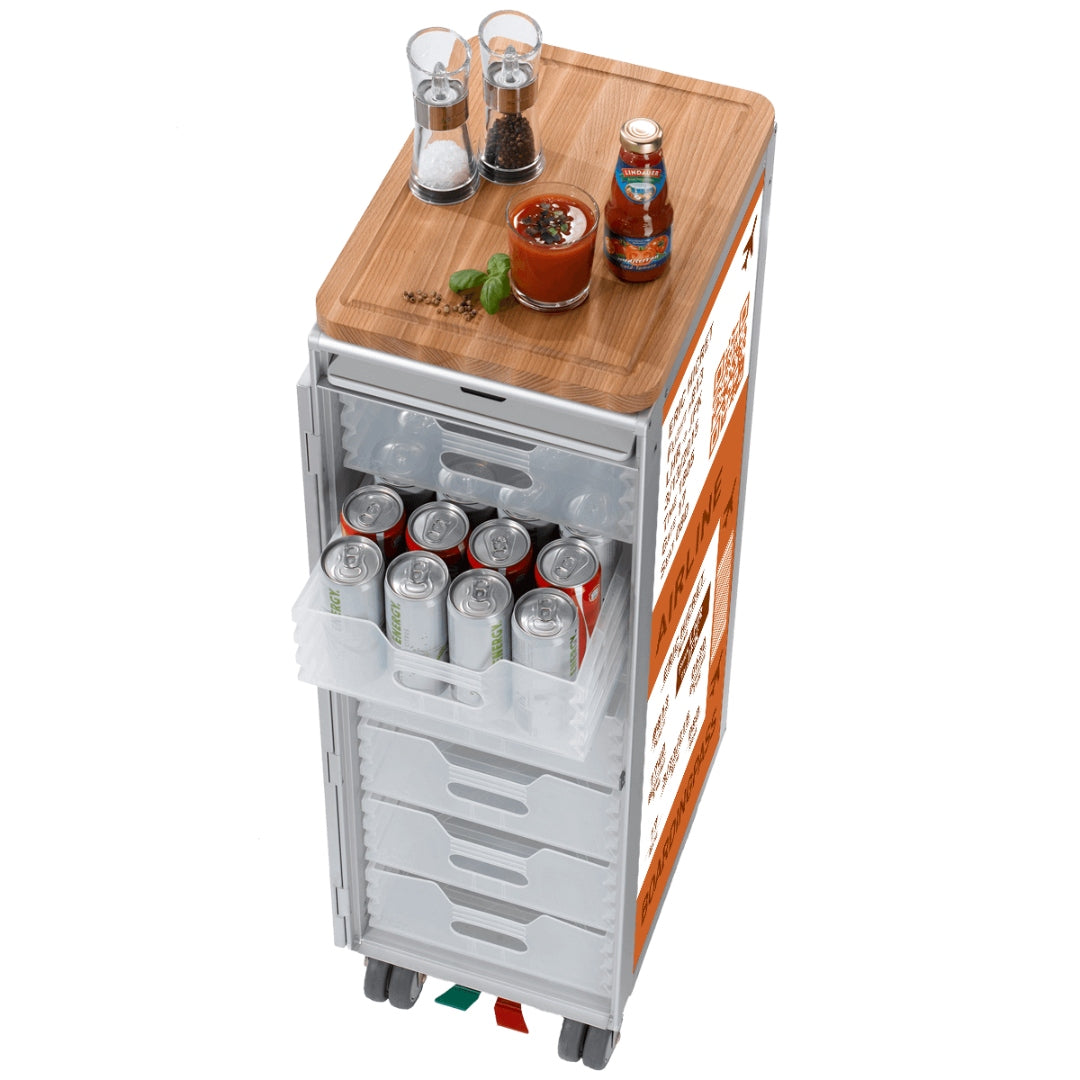 Grauer Catering-Wagen mit transparenten Auszügen, Getränkedosen, Holzbrett mit roter Sauce, LINDAUER-Flasche und Gewürzmühlen