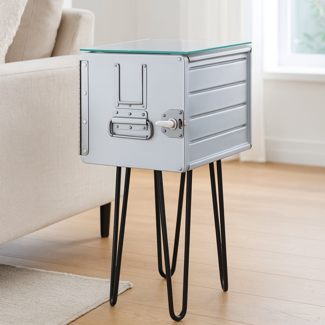 Grauer Metall-Beistelltisch mit Glastischplatte und schwarzem Hairpin-Gestell neben beigem Sofa auf hellem Holzboden