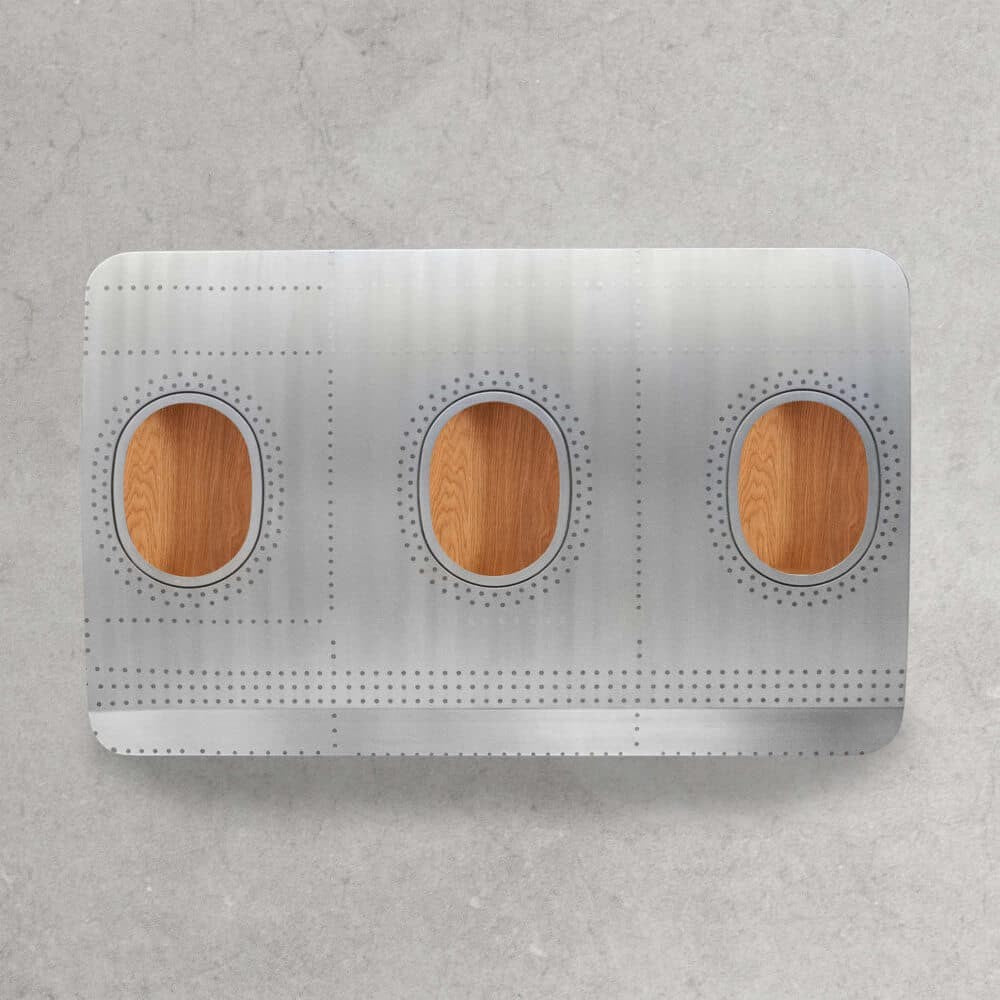 Metallpaneel mit drei ovalen Fensteröffnungen und Holzinnenseiten, im Design einer Flugzeugrumpfsektion.