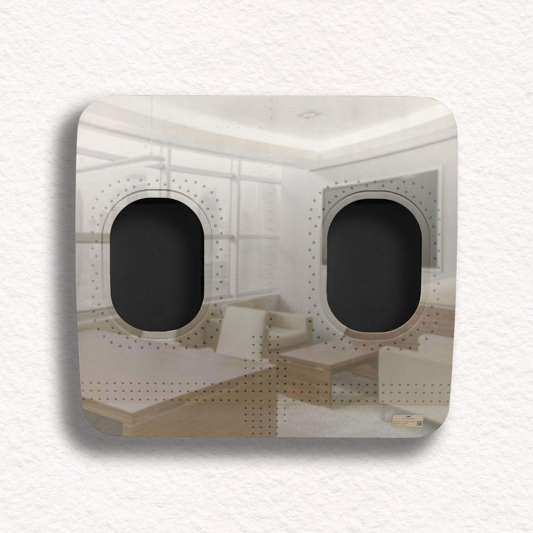 Metalltafel mit Flugzeugfenstern, die weiße Sofas und Fernseher im Zimmer reflektieren