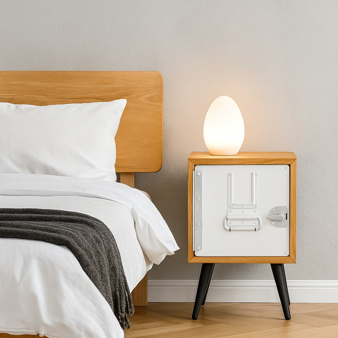 Moderne Schlafzimmerecke mit Holzbett, weißer Bettwäsche, grauer Strickdecke und Eierlampe.