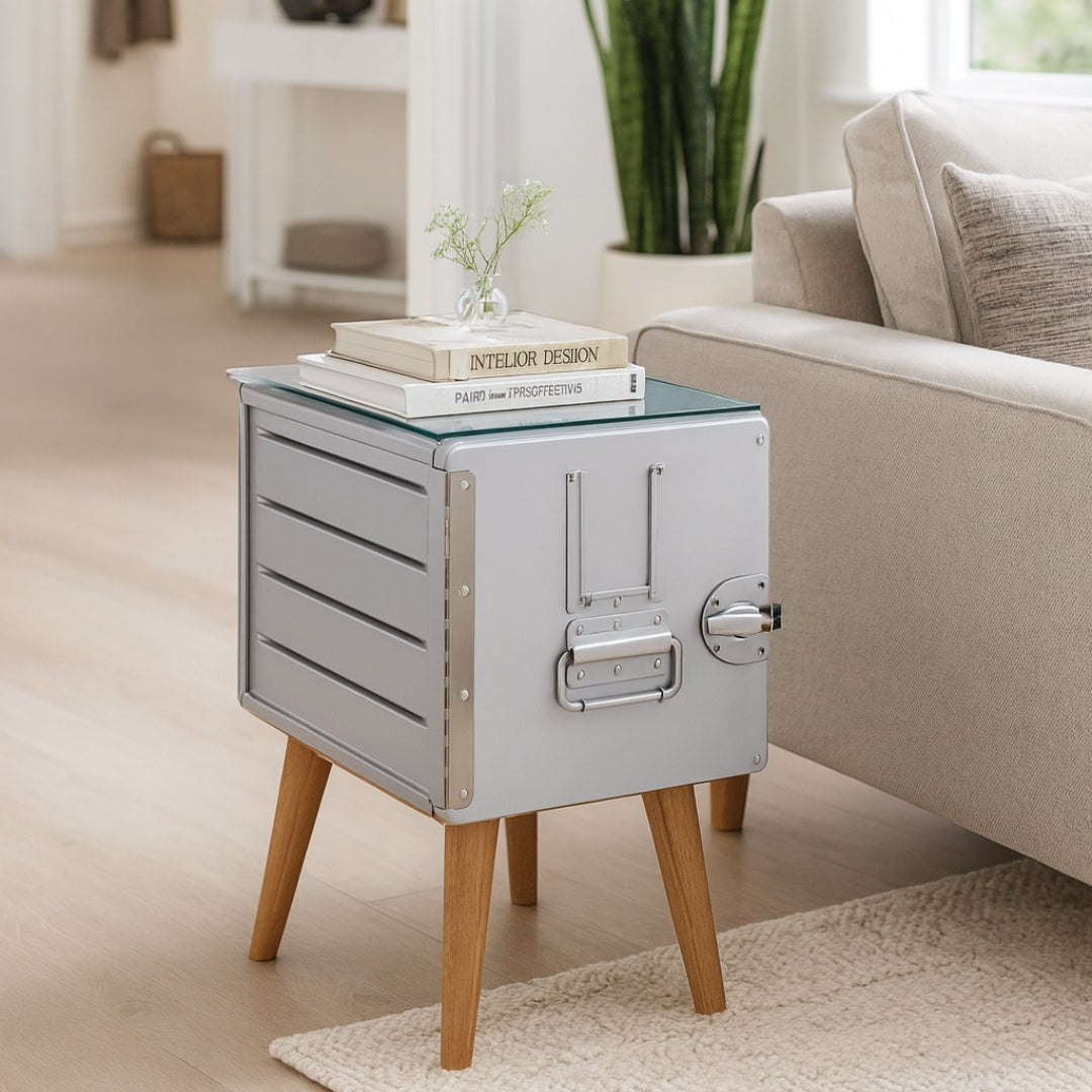 Moderner Metall-Beistelltisch mit Holzbeinen und Glasplatte, Bücher und Pflanzen im urbanen Wohnraum.