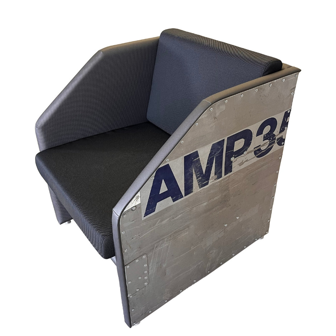 Moderner Stuhl mit dunkelgrauem Polster und metallischer Seitenfläche, blau beschriftet mit AMP35 und Nieten.