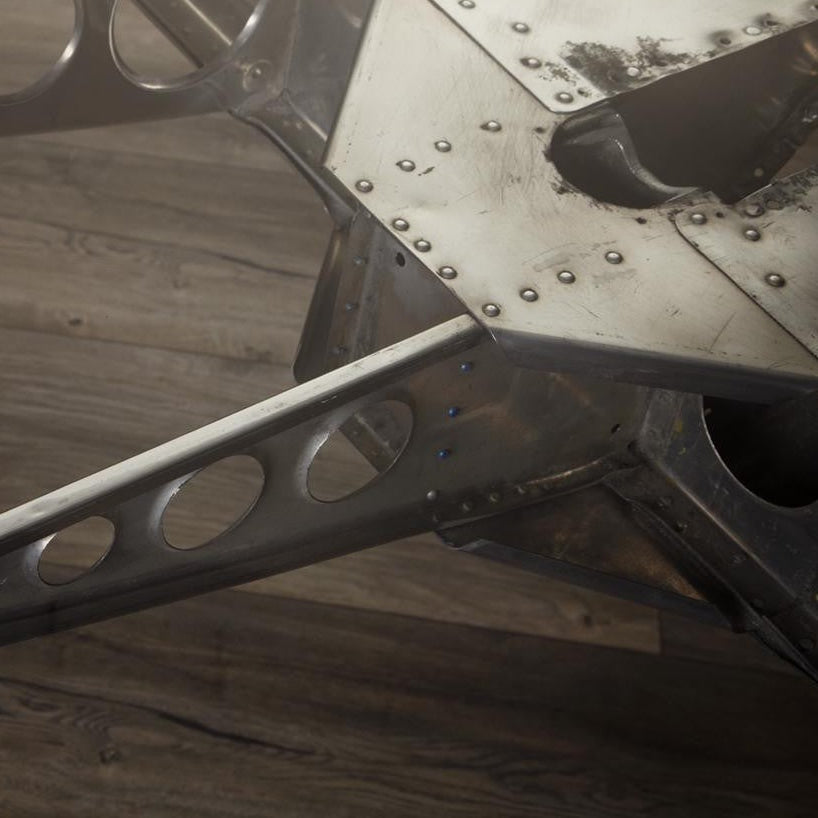 Nahaufnahme eines robusten Metallrahmens mit Nieten auf dunklem Holzfußboden.