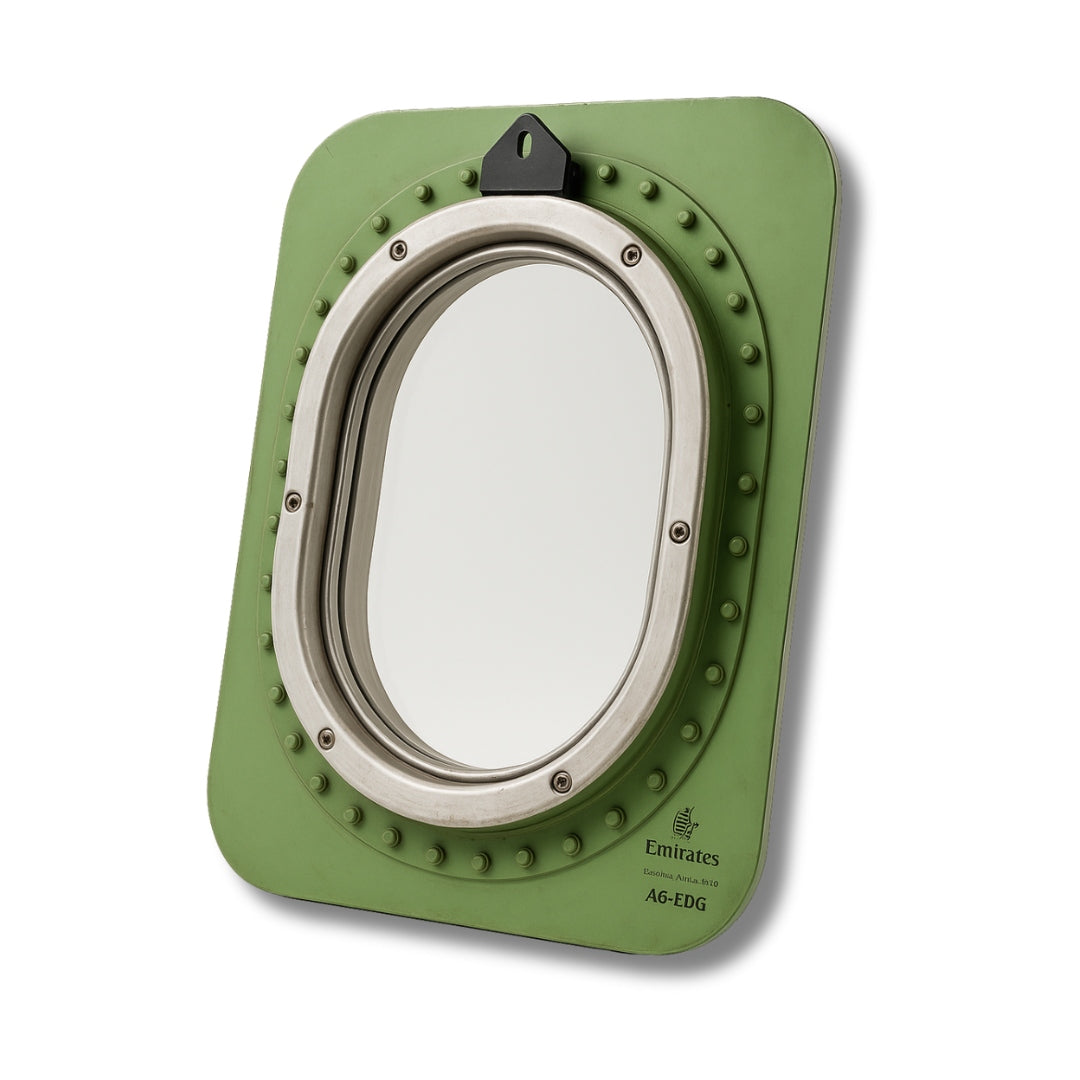 Ovales Flugzeugfenster mit grünem Rahmen, Schrauben und Emirates-Beschriftung sichtbar