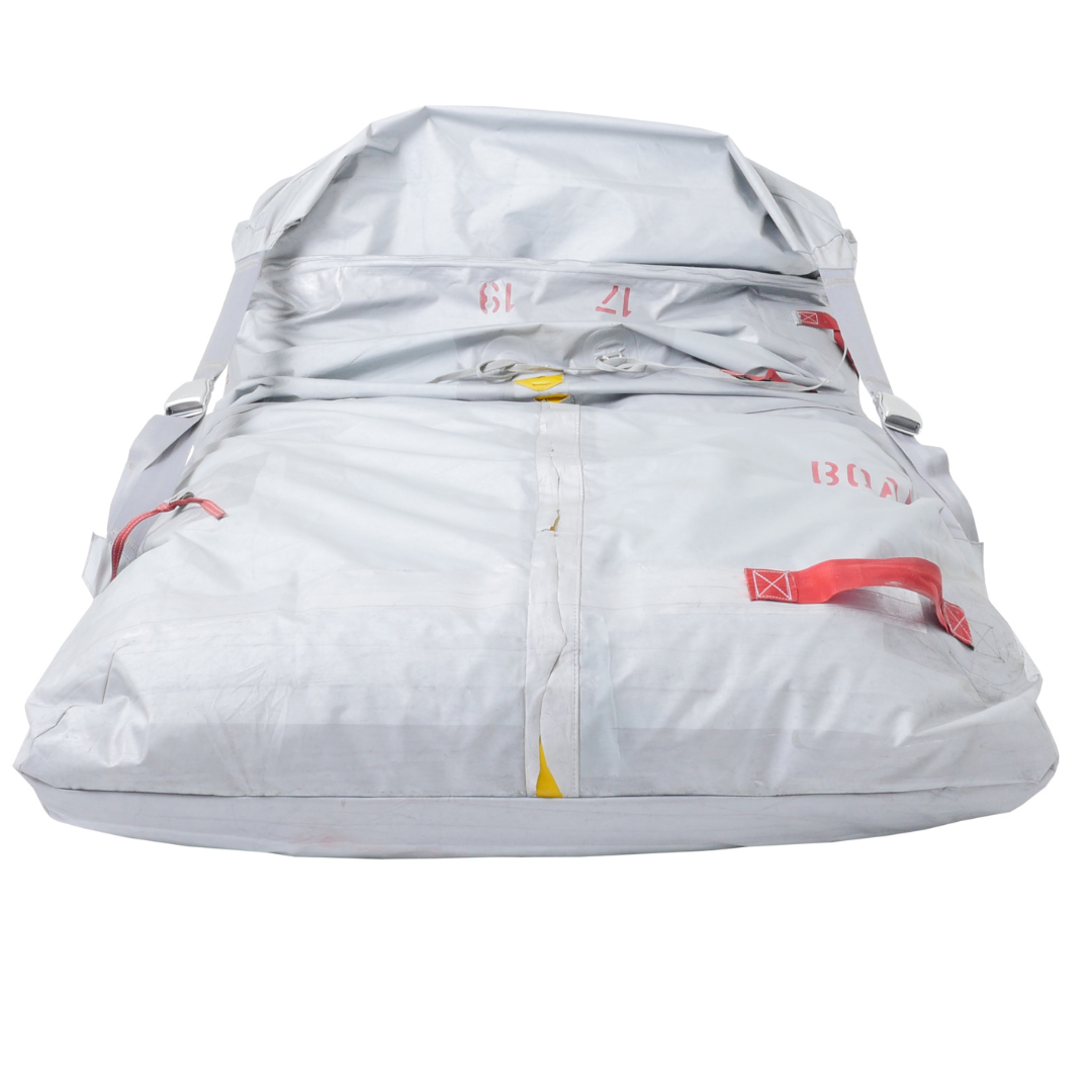 Weiß gefaltetes Rettungsfloß mit roten und gelben Sicherheitsakzenten sowie grauen Tragegurten.